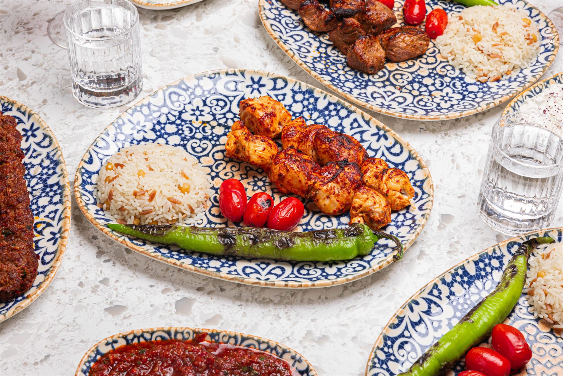 Charcoal-grilled kebabs and rice on patterned plates